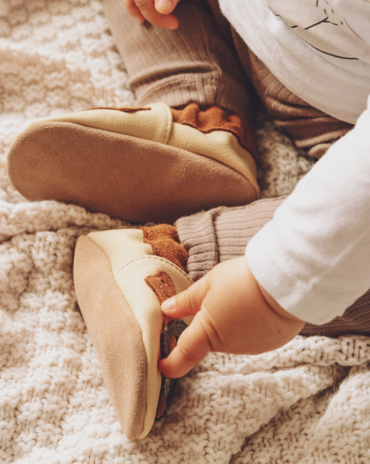Baby mit Krabbelschuhen Schildkröte beige
