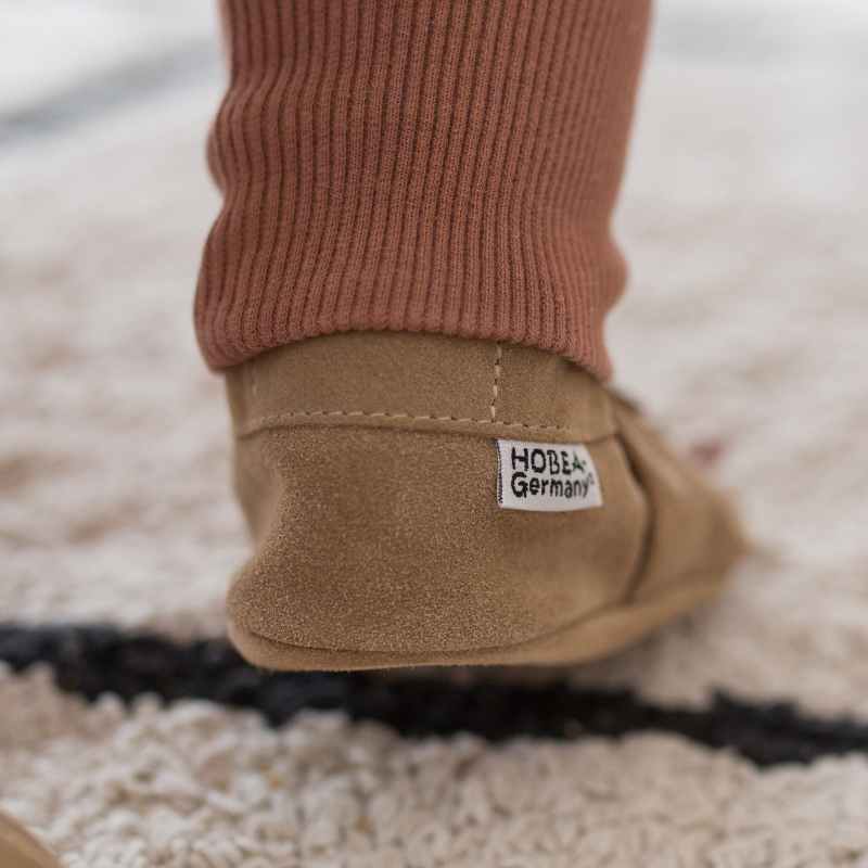 Kind trägt Krabbelschuhe Kind trägt Krabbelschuhe auf hellem Teppich